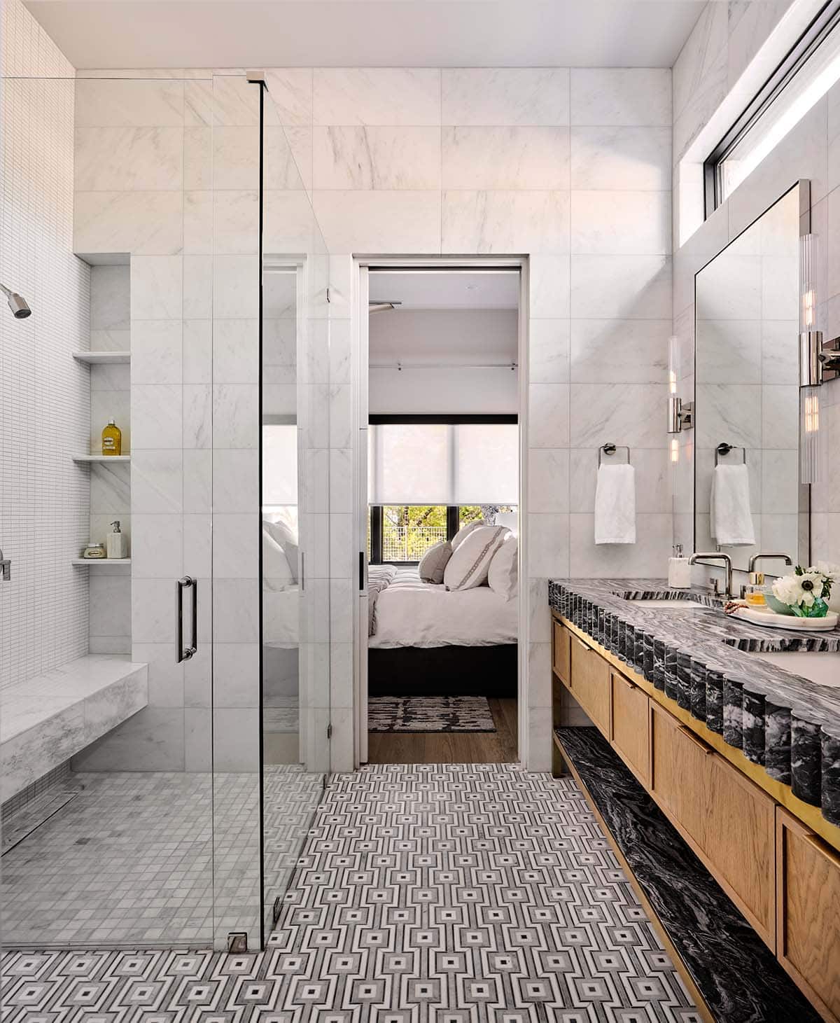 Guest bathroom with bold geometric mosaic floor tile, dark marble scalloped vanity, and marble shower