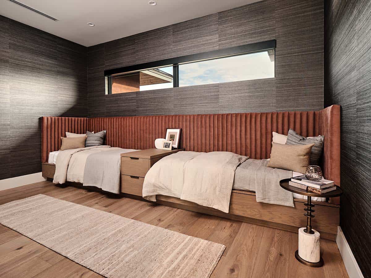 Guest bedroom with twin beds, full-length terracotta channeled headboard wall, and dark grasscloth wallpaper