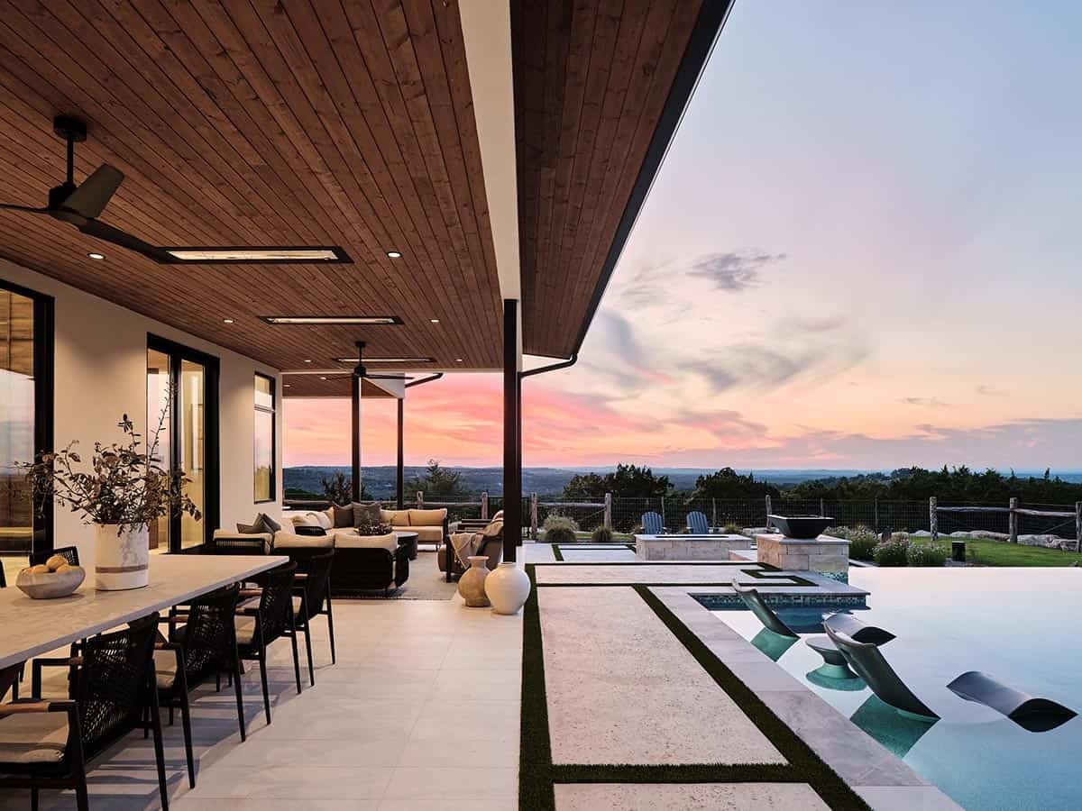 Covered outdoor living and dining area with infinity pool, fire pit, and sweeping Texas Hill Country sunset views