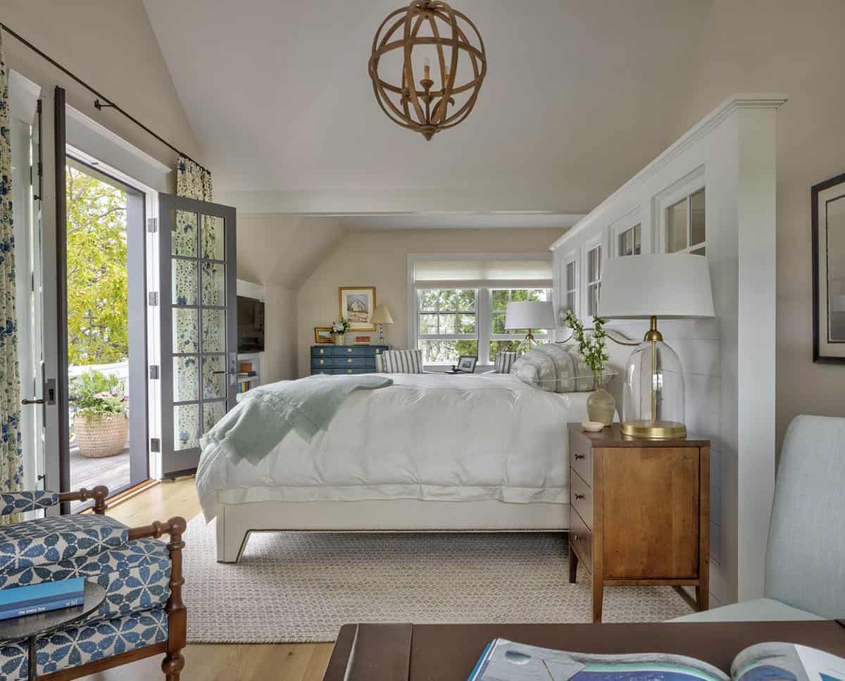 Guest cottage bedroom with wood orb chandelier, white bedding, blue floral curtains, French doors to balcony, and walnut nightstands