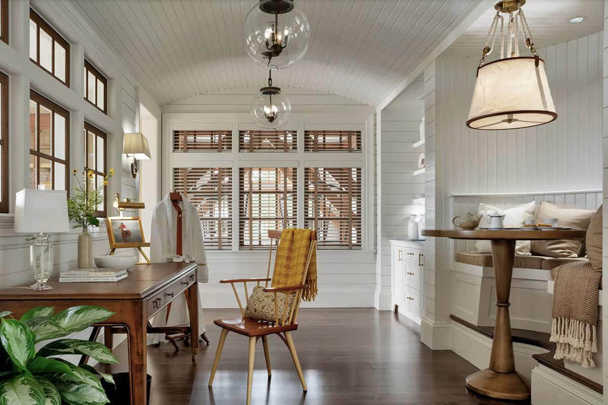 Barn-style sitting room with shiplap walls, barrel-vault ceiling, glass globe pendant, writing desk, Windsor chair, and built-in corner banquette