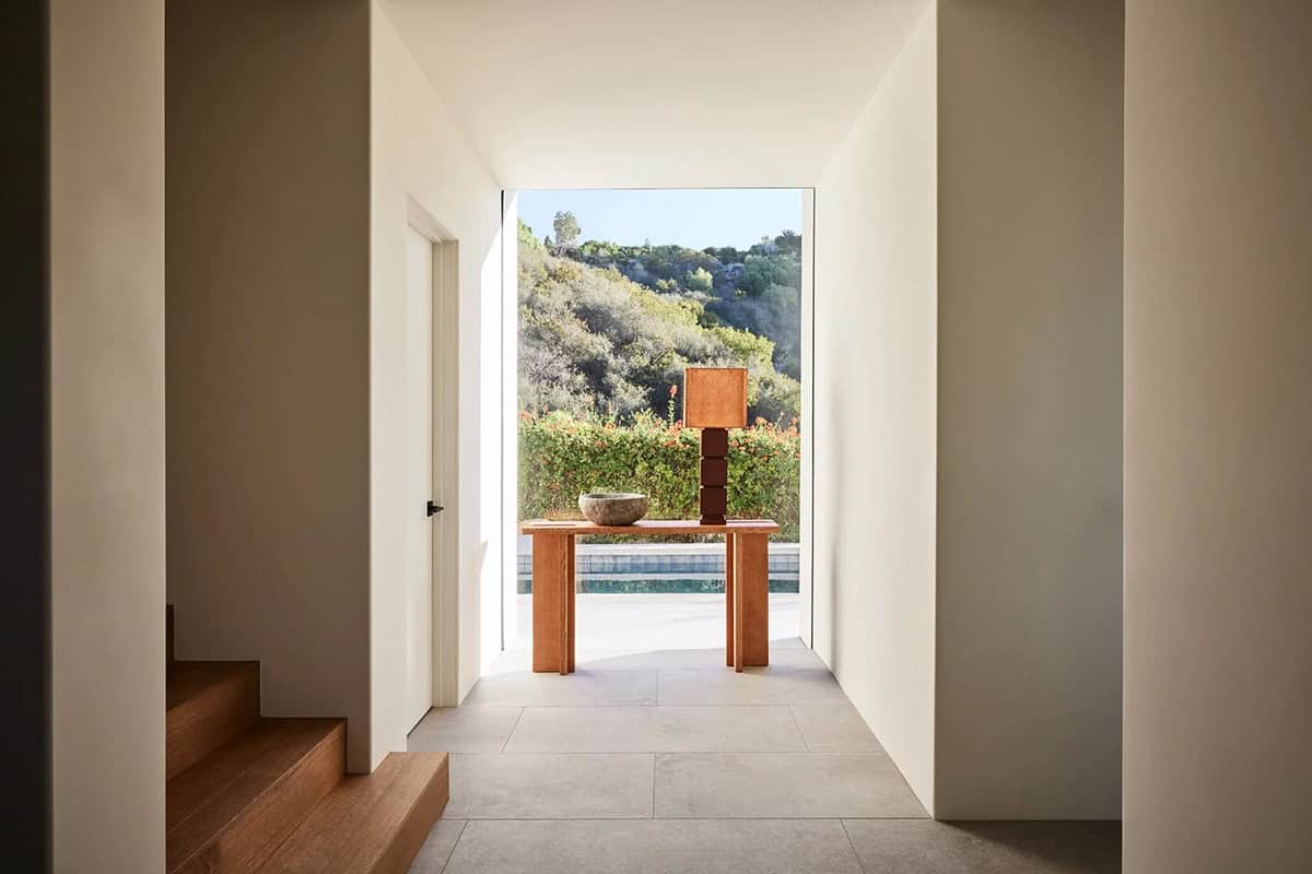 Bright hallway with wood console table, stone bowl, and panoramic hillside view through open doorway