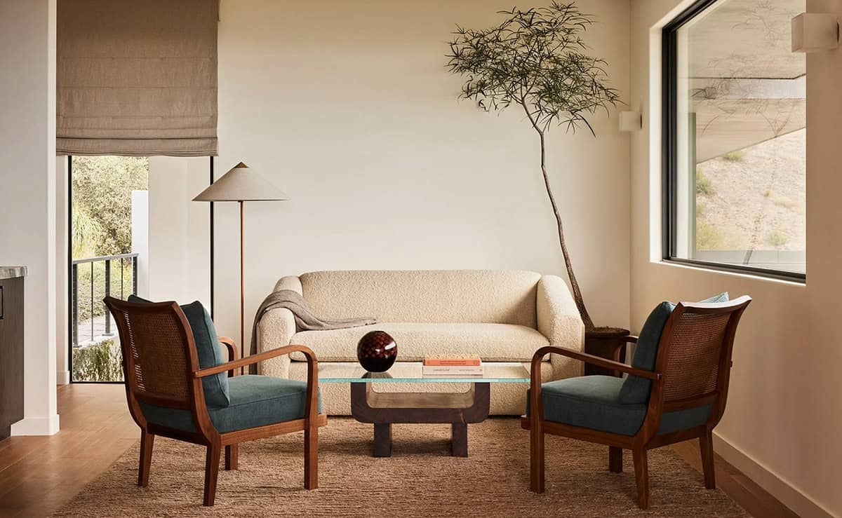 Sitting room with boucle sofa, teal cane armchairs, sculptural coffee table, and bamboo tree