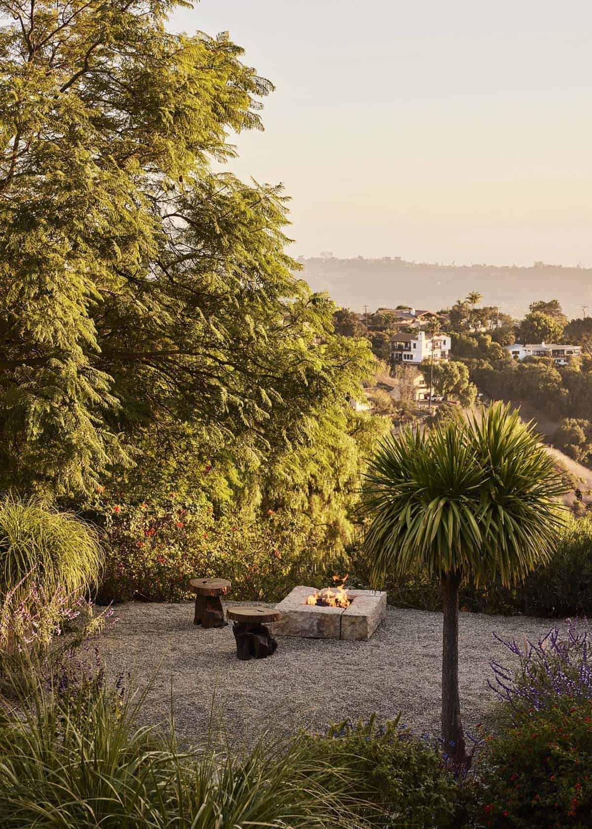 Gravel garden fire pit with wood stool, yucca palm, and golden hour hillside views