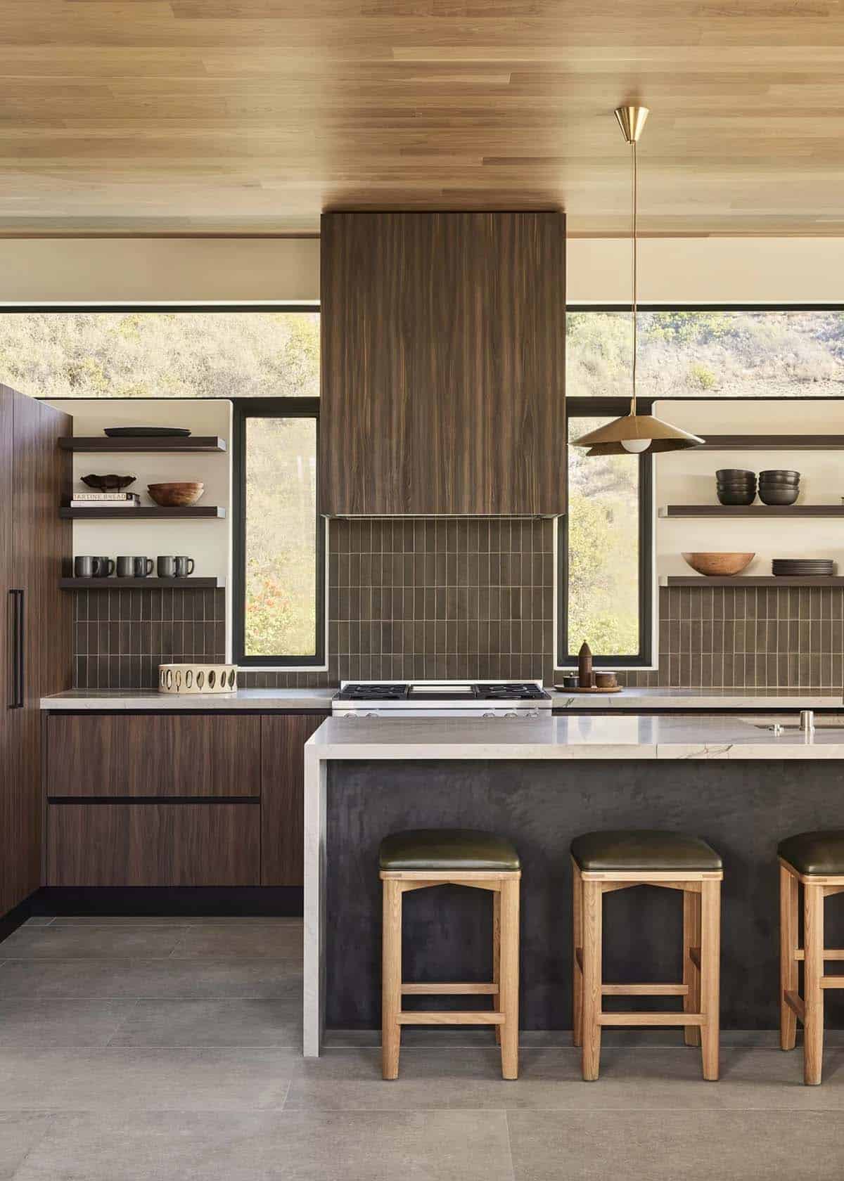  Kitchen with dark walnut hood, vertical green tile backsplash, open shelving, and green leather stools