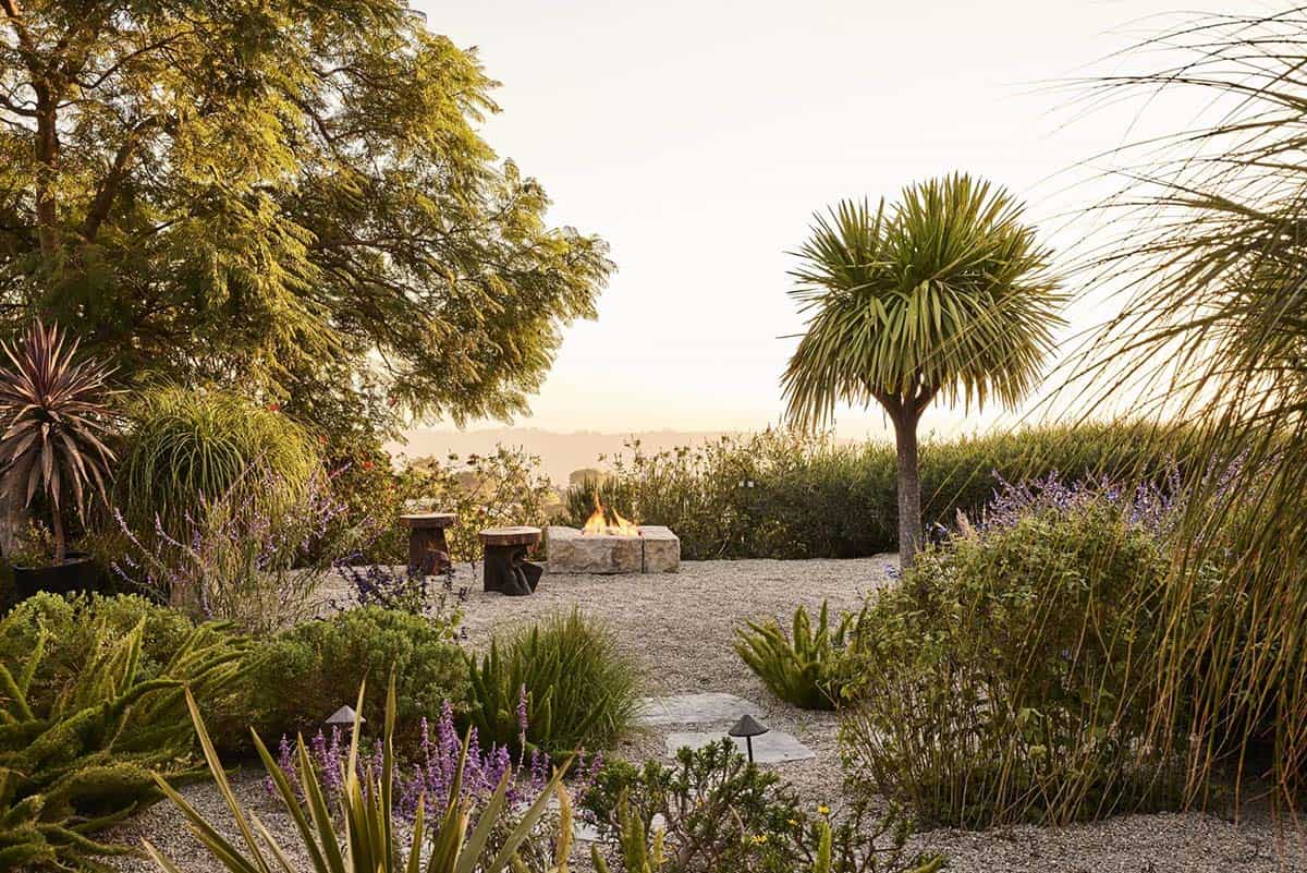 Gravel garden fire pit with wood stool, yucca palm, and hillside views