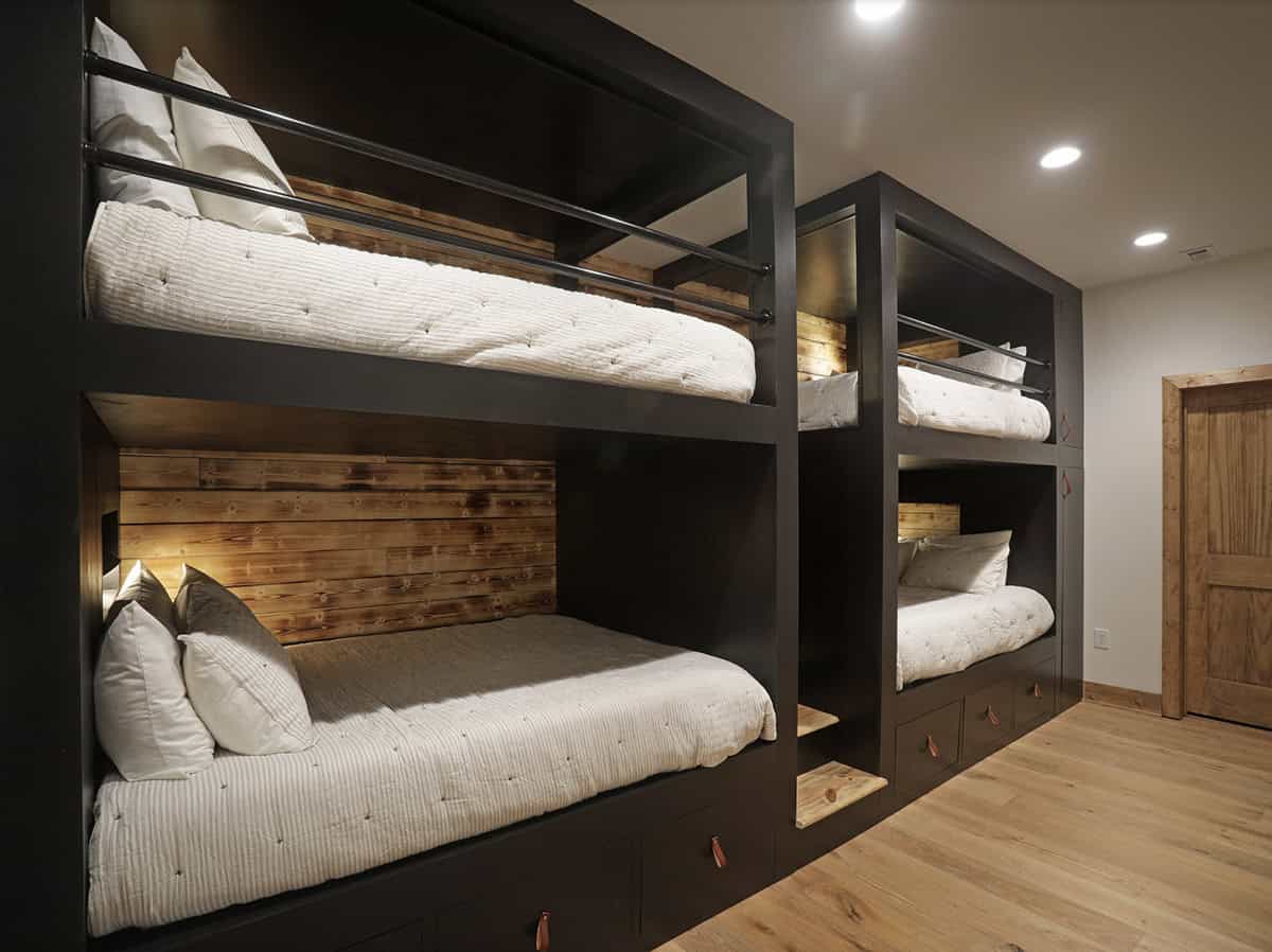 Built-in dark wood bunk beds with warm wood headboard panels and leather drawer pulls