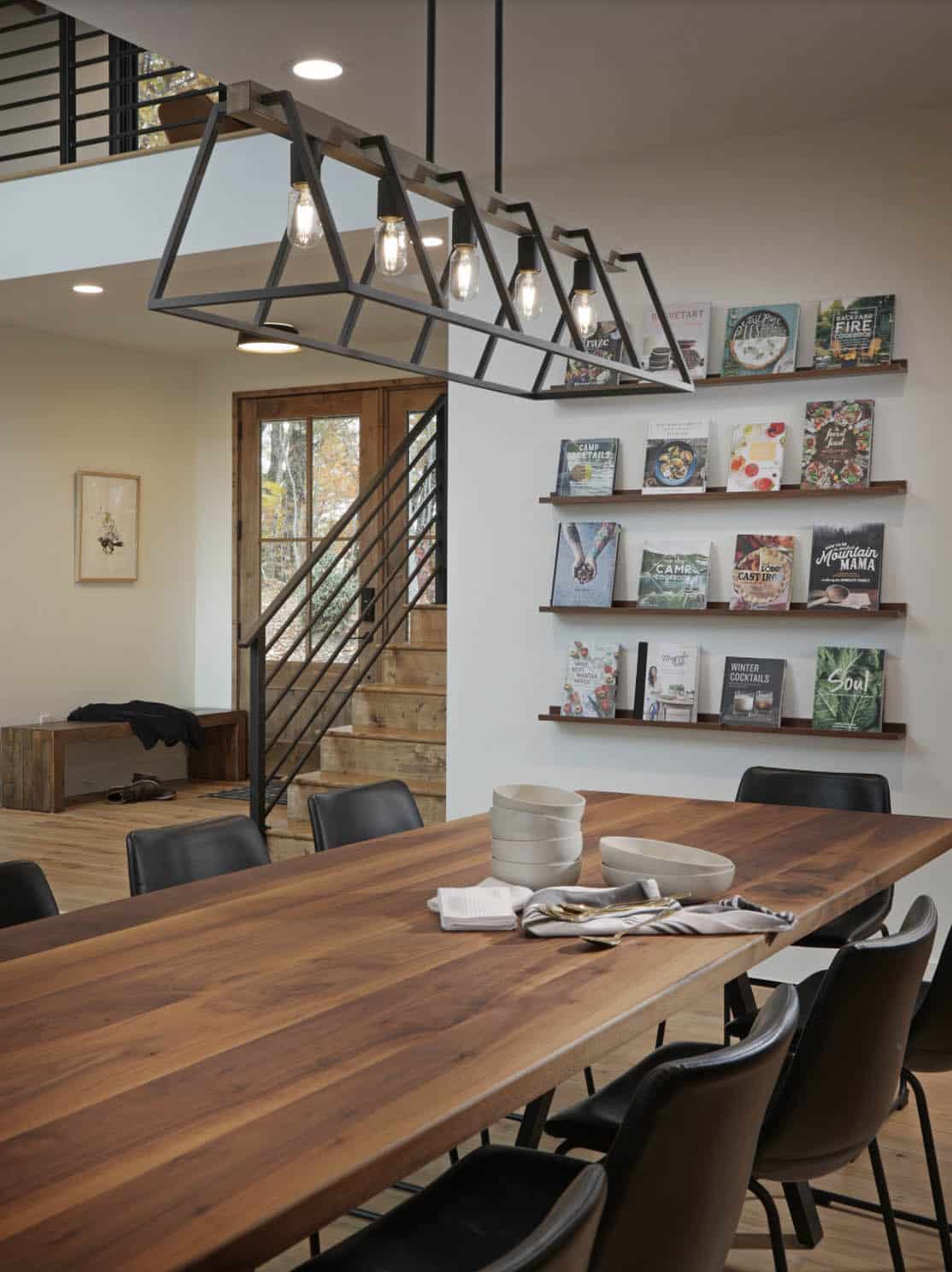 Dining room with walnut table, industrial pendant light, and wall-mounted cookbook shelves