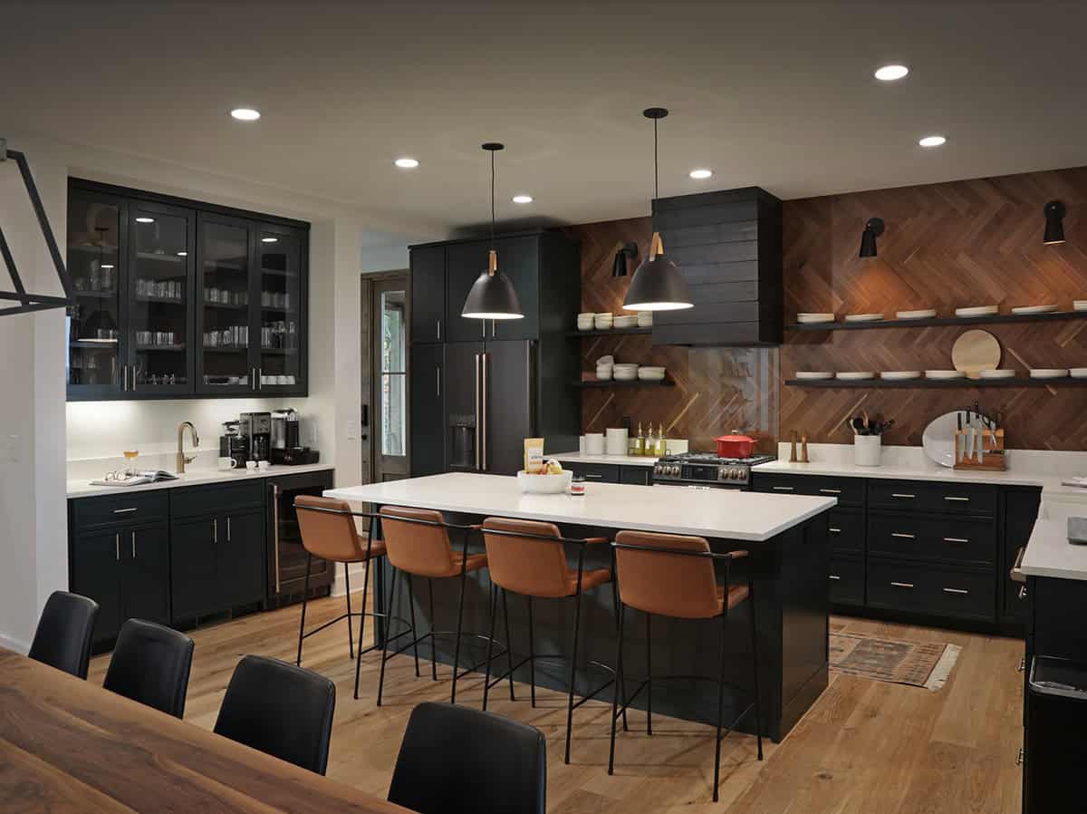 Dark kitchen with herringbone wood backsplash, white quartz island, and leather barstools