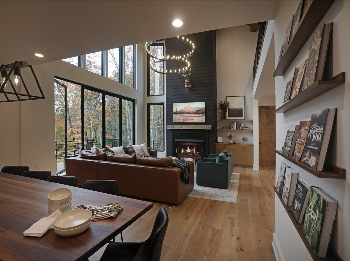 Great room view from dining area showing fireplace wall, book ledges, and mountain windows