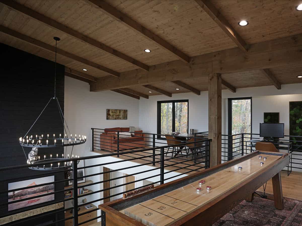 Loft game room with shuffleboard table, exposed timber beams, and wagon wheel chandelier