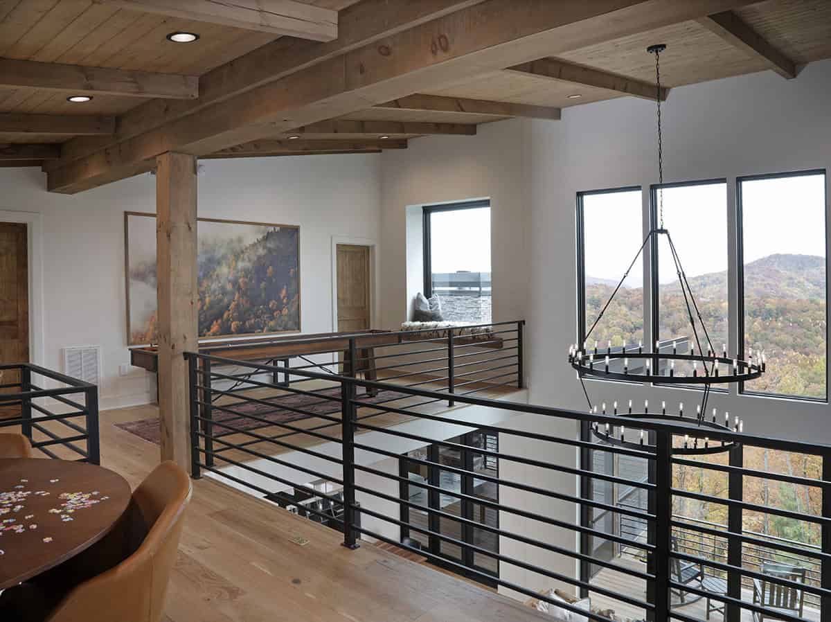 Loft hallway with timber beam ceiling, black iron railings, and mountain views
