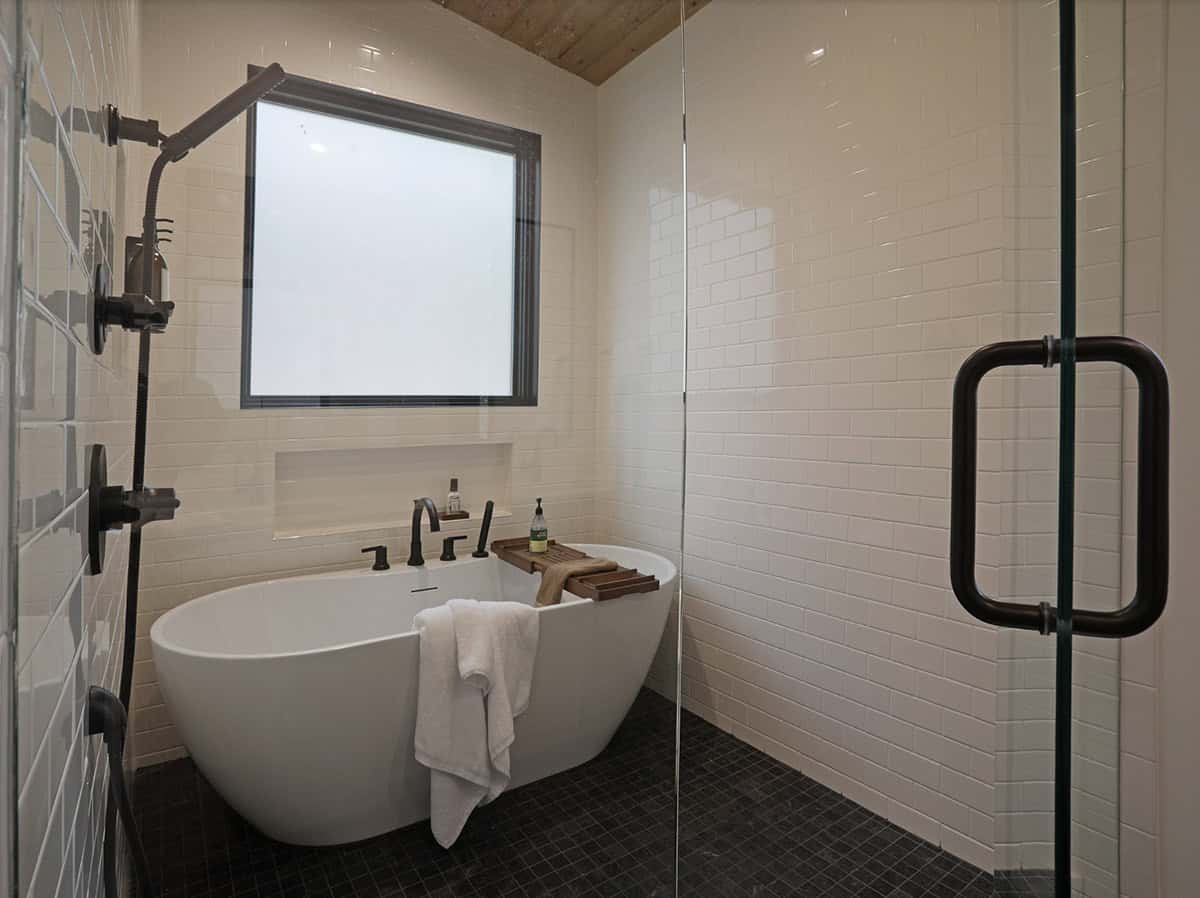 Bathroom with freestanding soaking tub, subway tile, dark fixtures, and wood ceiling
