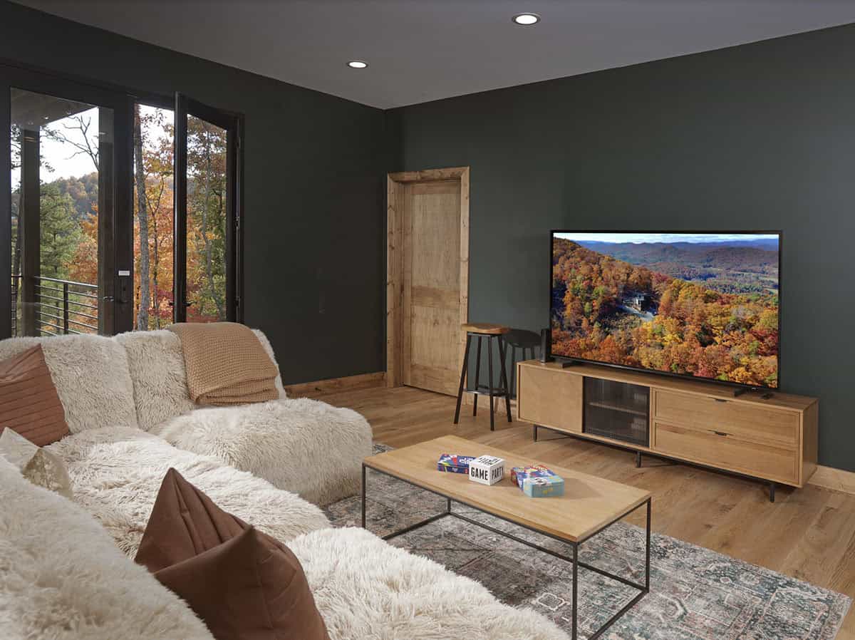 Media room with dark green walls, plush white sectional, and large TV