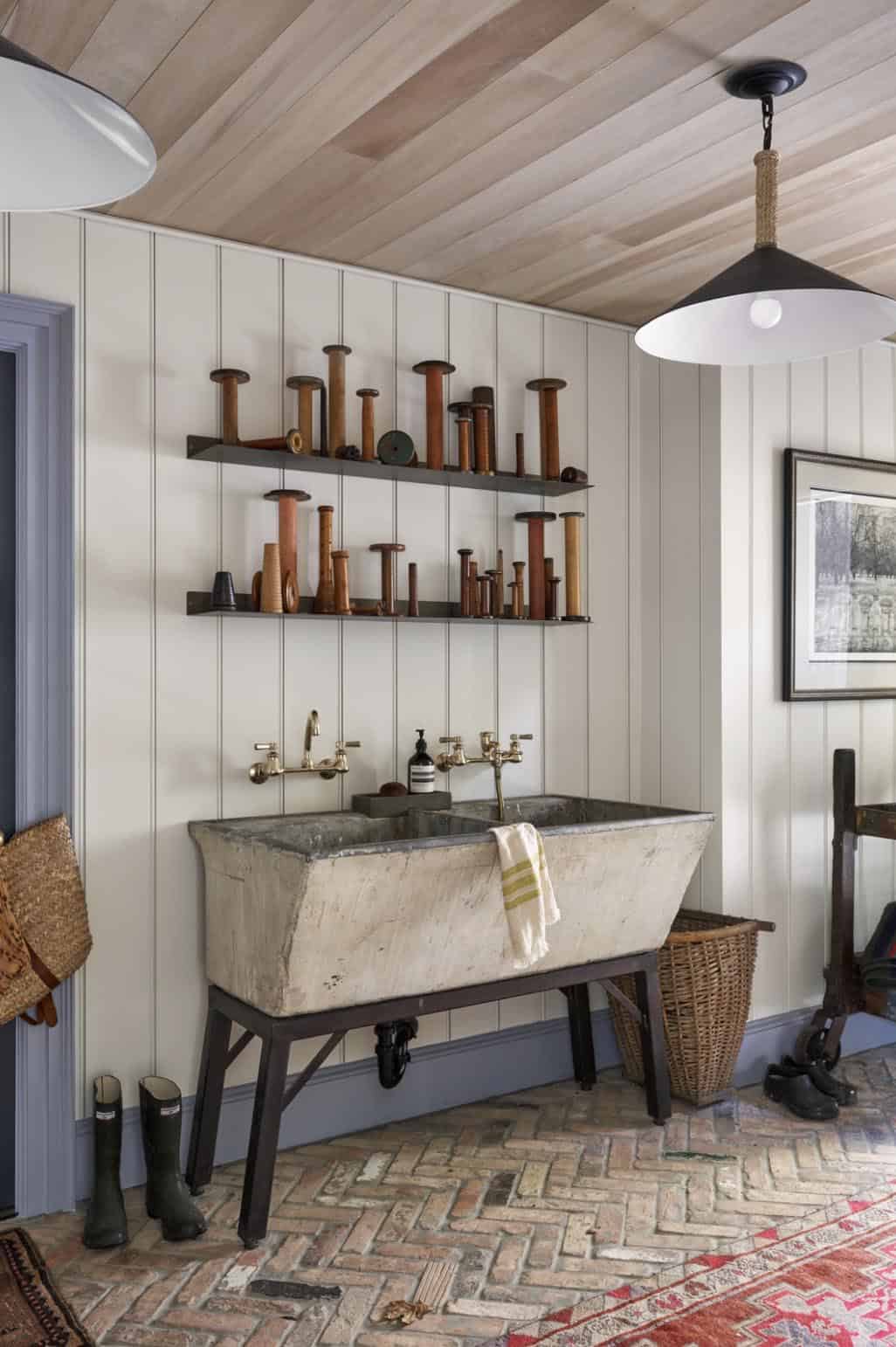 Mudroom with antique stone laundry sink, brass faucets, vintage spool collection, and herringbone brick floor
