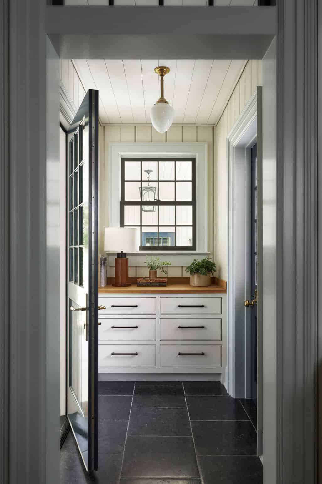 Transitional mudroom hallway with built-in white drawers, wood countertop, and brass pendant light