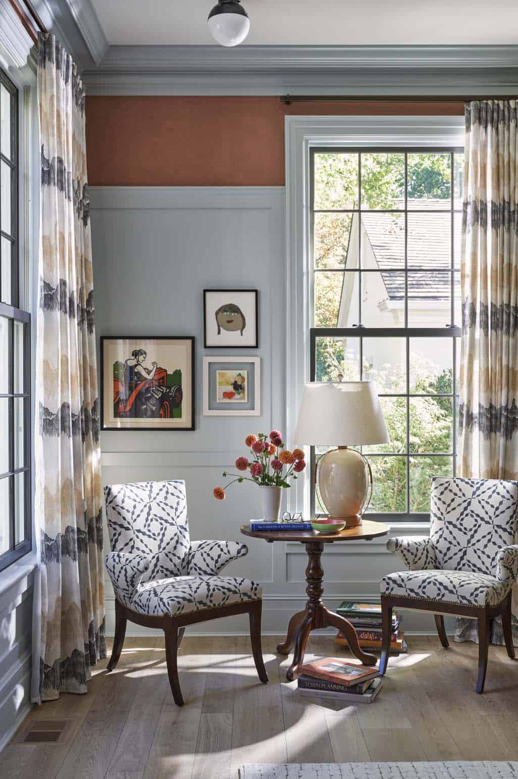 Sitting room corner with two patterned armchairs, terracotta upper walls, and paneled wainscoting