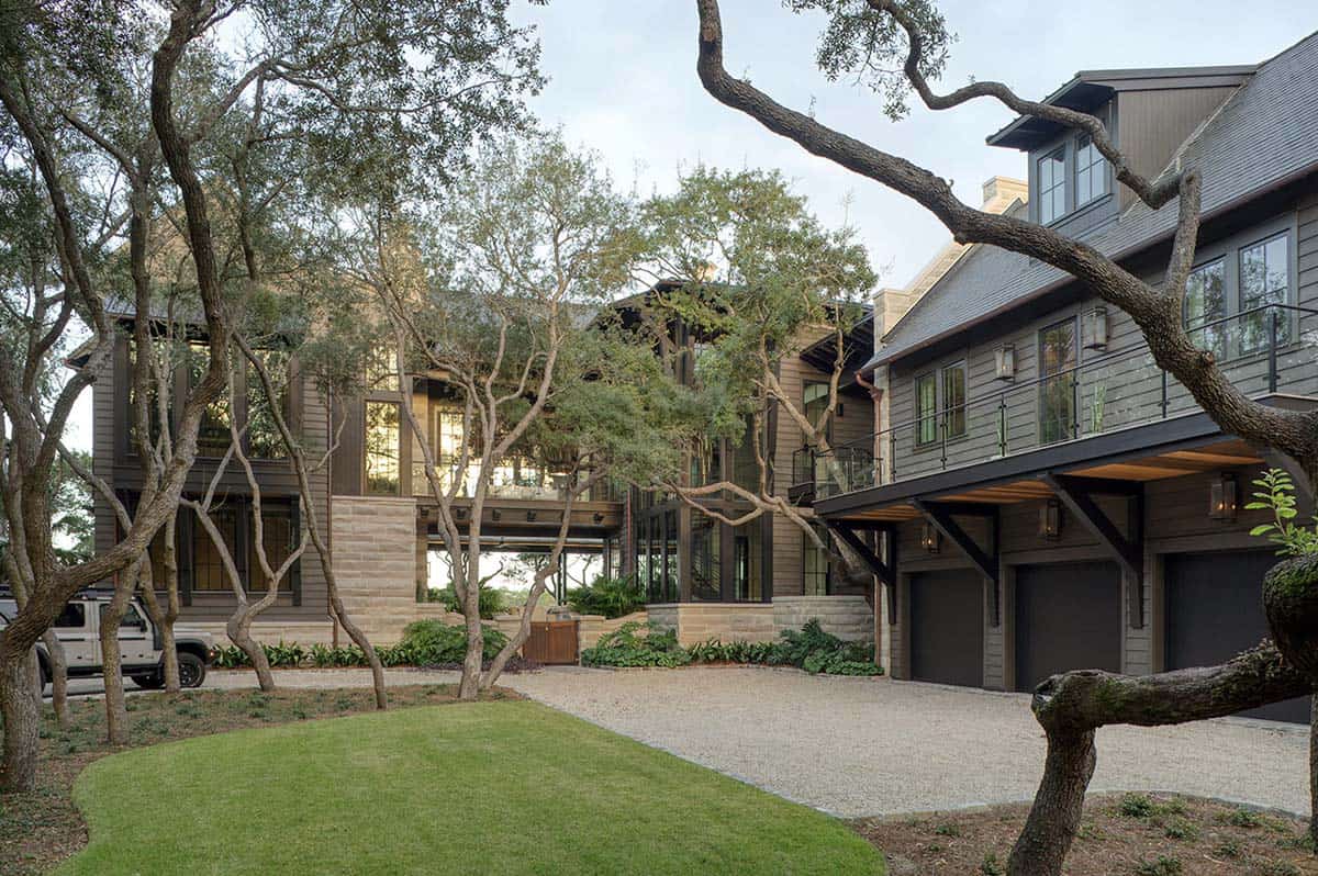 Modern lake house exterior with gray siding balcony and gravel driveway