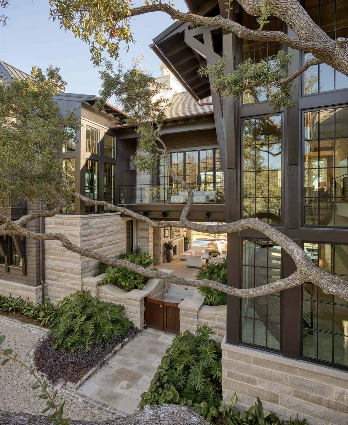 Lake house courtyard entry with stone walls large windows and tropical landscaping