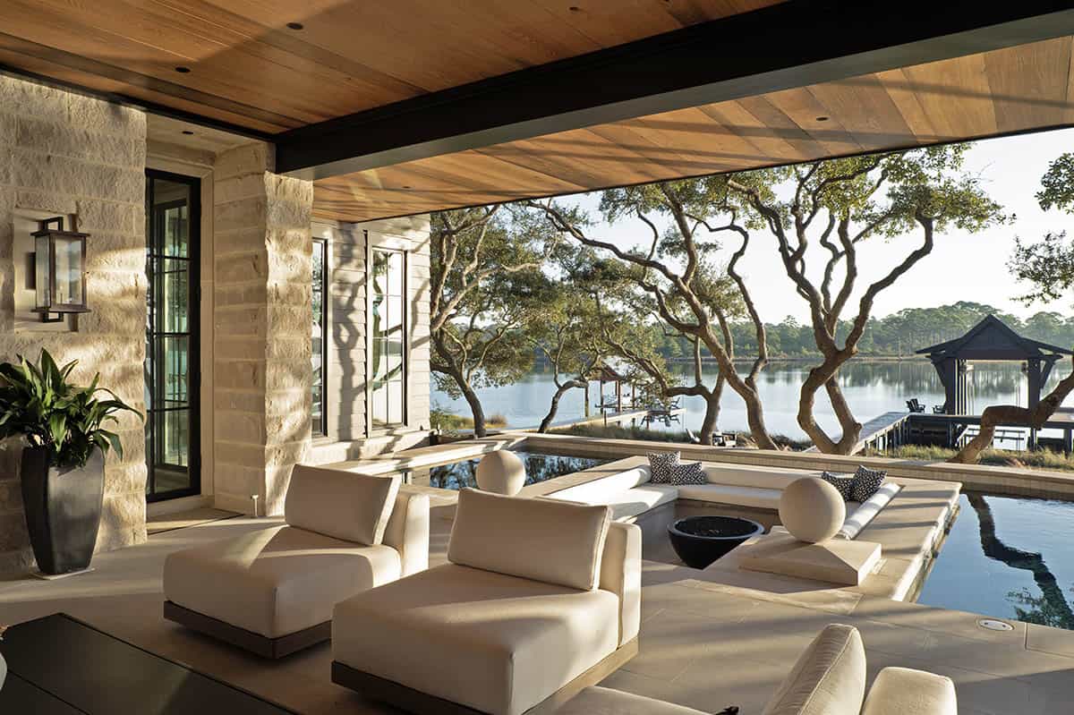 Covered outdoor living area with lake views pool and white seating