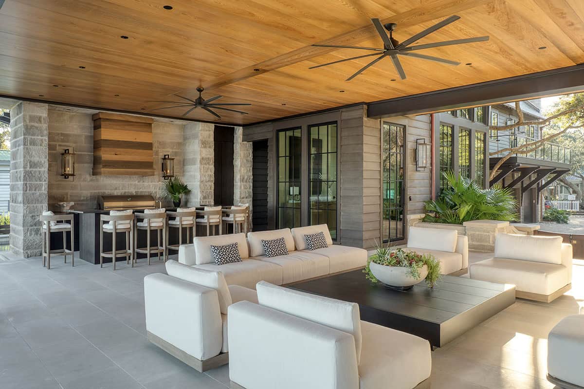 Covered outdoor kitchen and living area with wood ceiling and stone columns