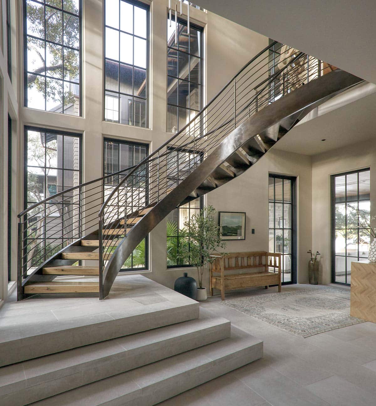 Grand entryway with curved steel staircase floor to ceiling windows and herringbone tile