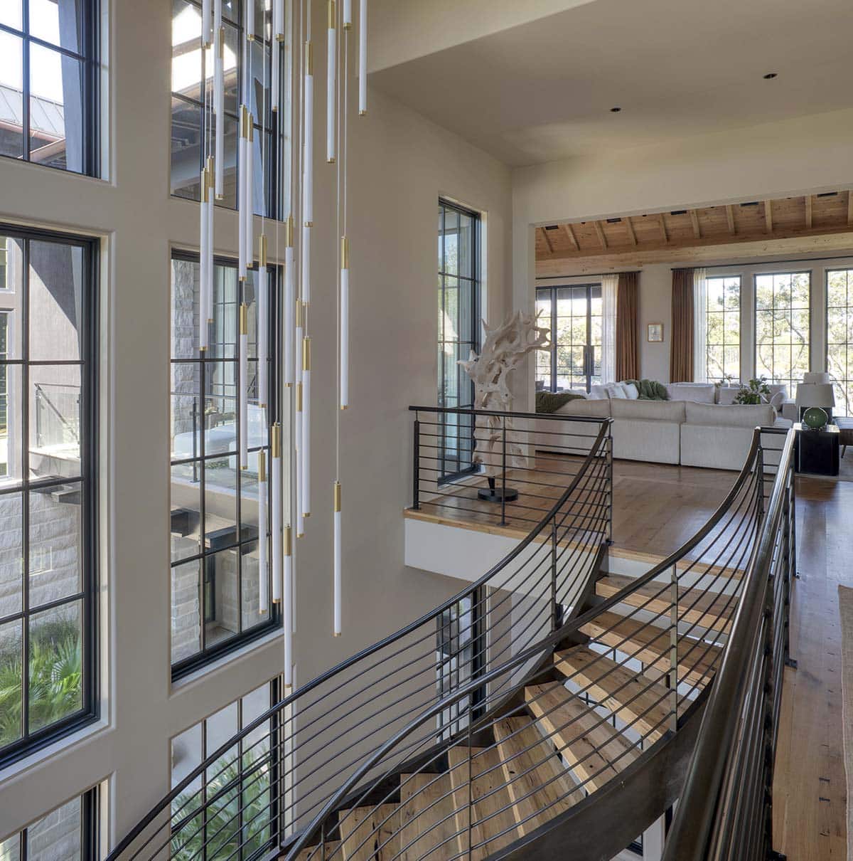 Upper landing with curved staircase statement chandelier and open living room