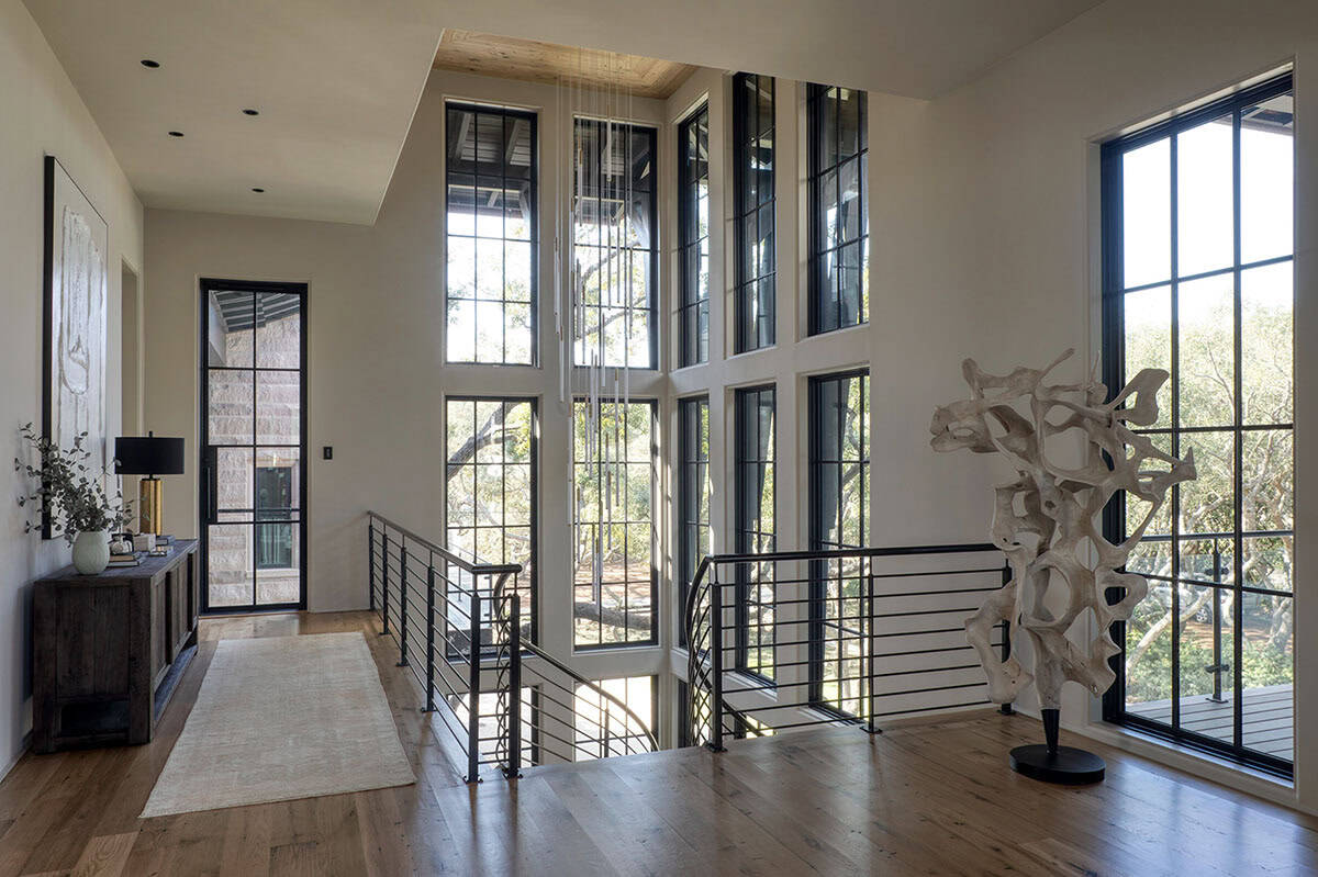 Upper hallway with floor to ceiling windows steel railing and sculptural artwork