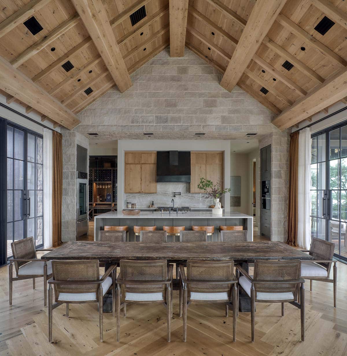 Open plan dining room and kitchen with vaulted wood beam ceiling and stone walls