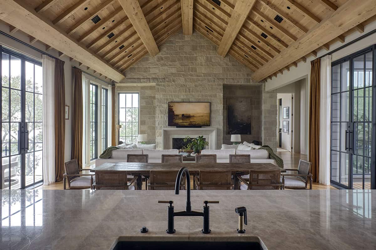Open plan living dining and kitchen with vaulted wood beam ceiling and stone fireplace
