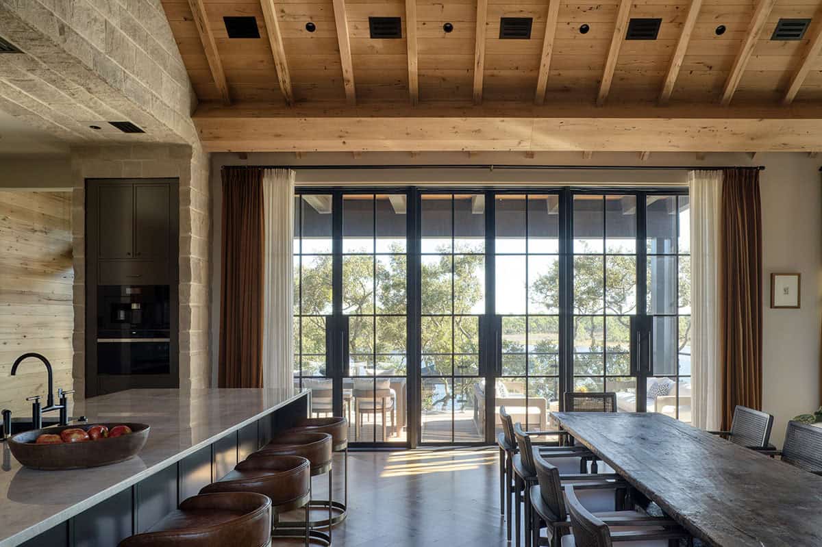 Kitchen with dark island marble countertop and steel frame doors to lake view