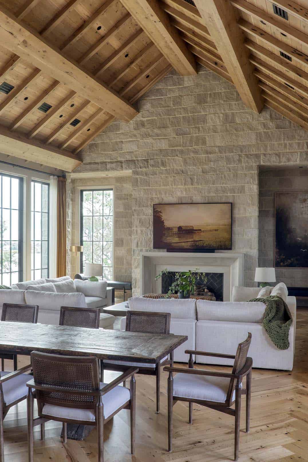 Living room with vaulted wood beam ceiling stone fireplace and white sofas