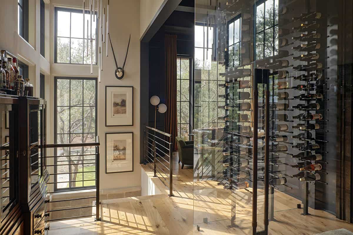 Glass enclosed wine cellar with floor to ceiling bottle display and bar area