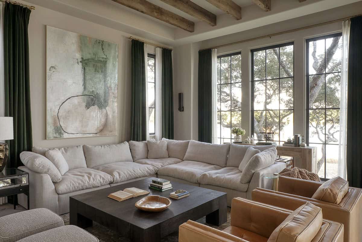 Living room with sectional sofa leather chairs exposed beams and large windows