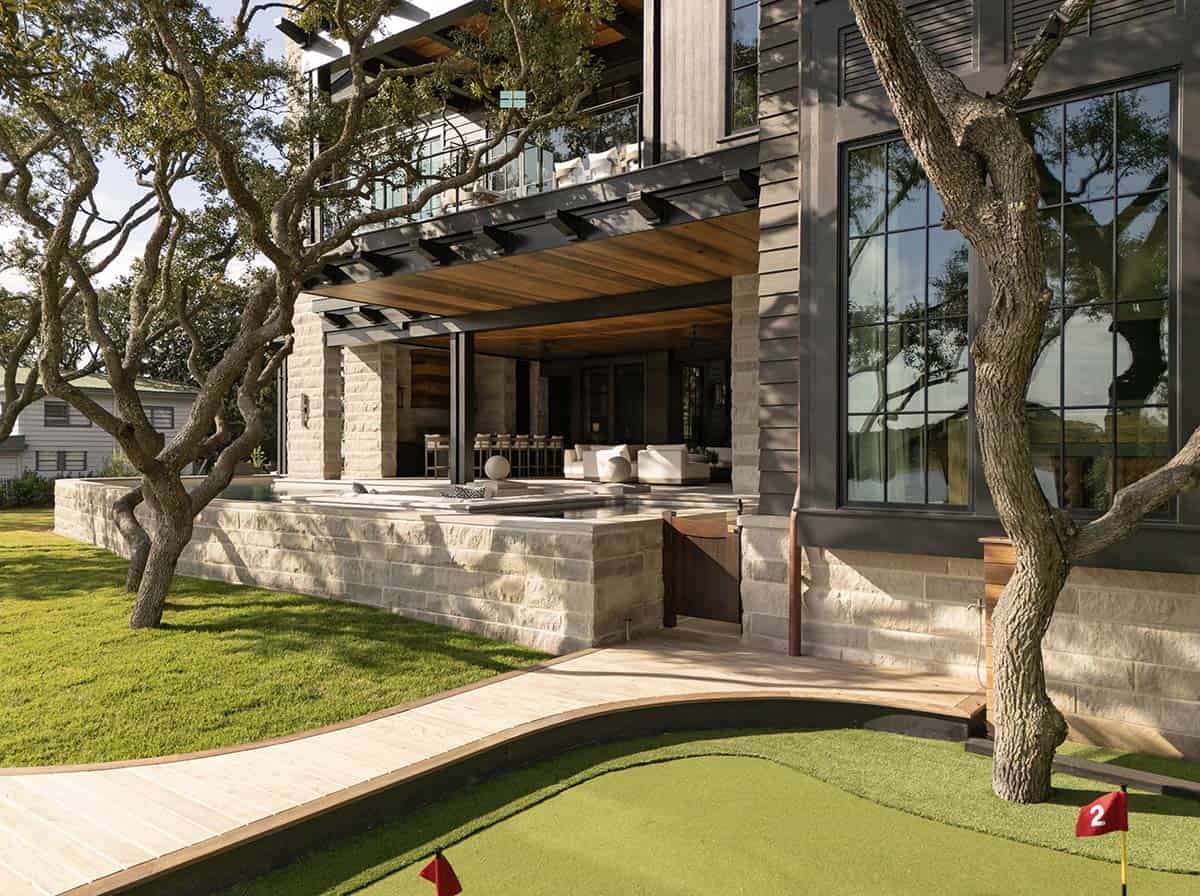 Lake house rear exterior with putting green stone base and covered porch