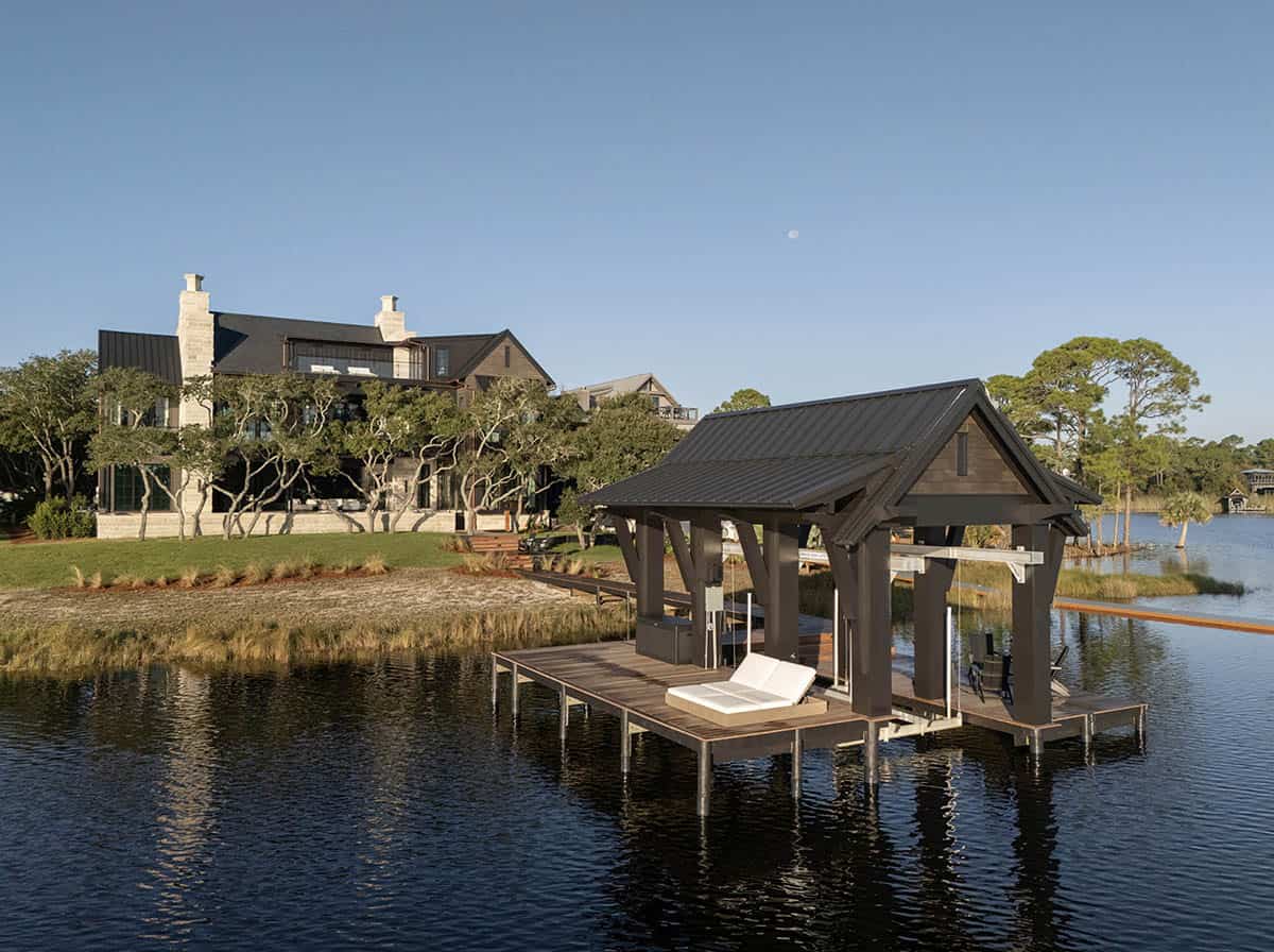 Covered boat dock with metal roof over lake with lake house in background