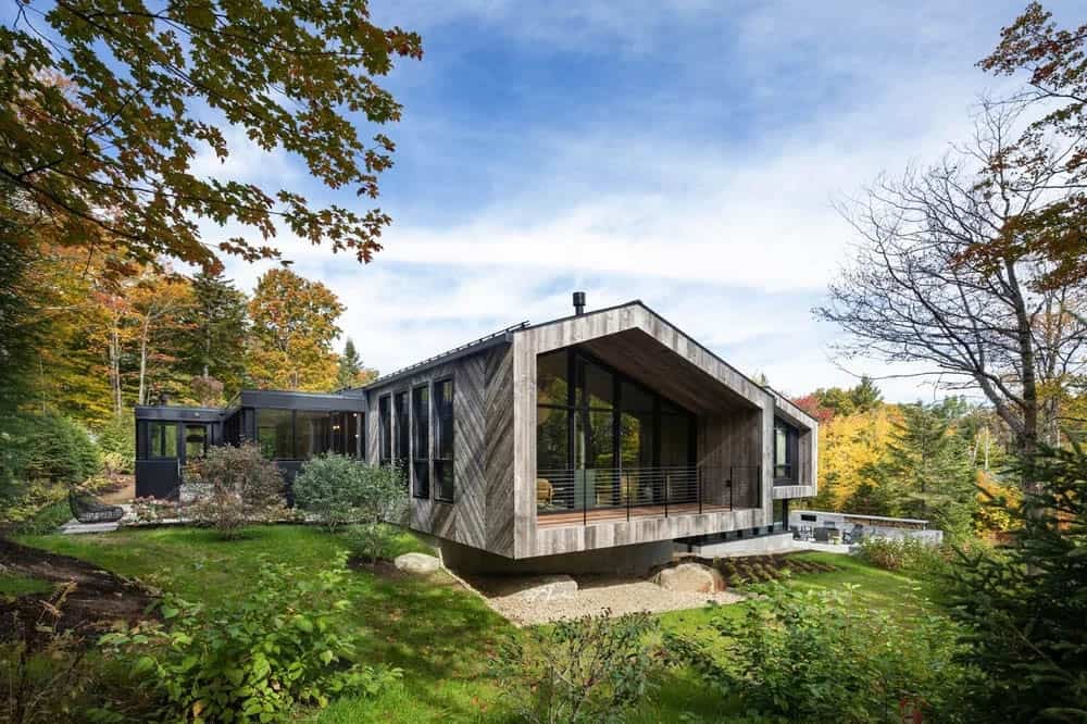 Side view of modern mountain home with weathered wood chevron cladding cantilevered over rocky landscape