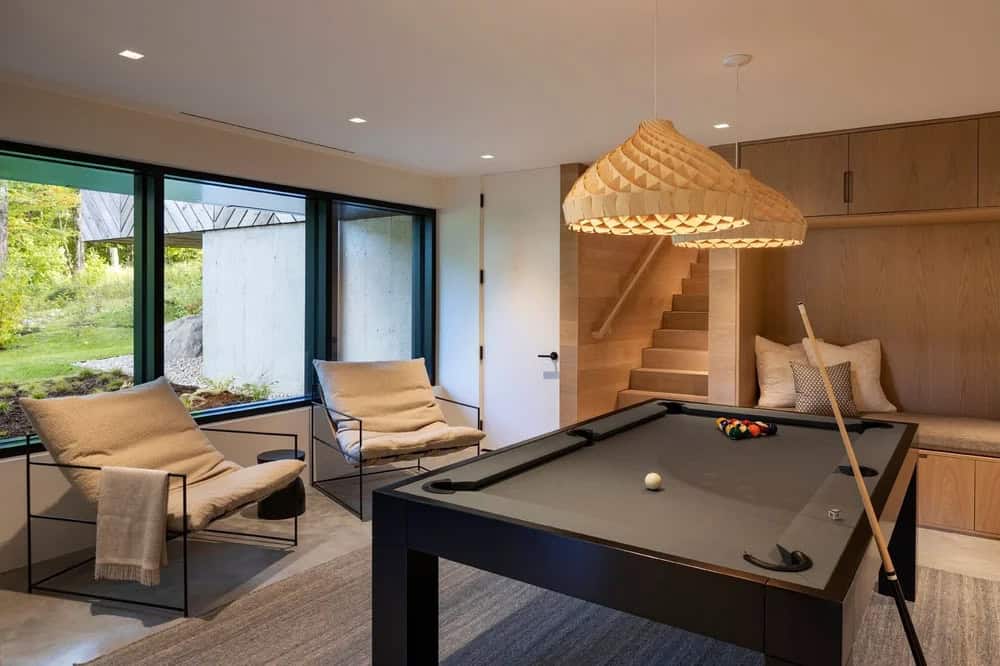 Game room with pool table, sculptural wood pendant lamp, built-in bench seating, and oak staircase