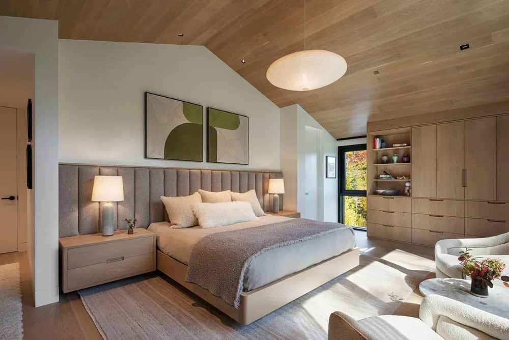 Primary bedroom with vaulted white oak ceiling, upholstered headboard, built-in wardrobe, and abstract green artwork