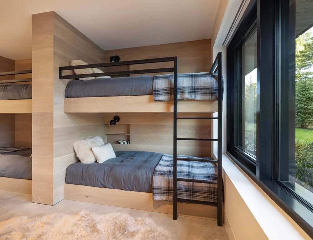 Built-in oak bunk beds with black metal ladder, individual reading lights, and large forest-view windows