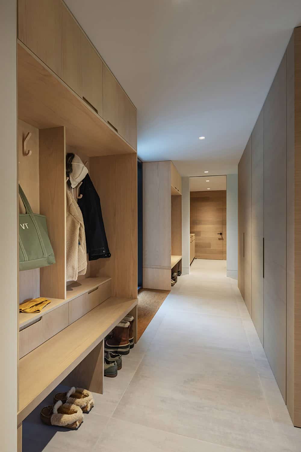 Mudroom hallway with built-in oak lockers, coat hooks, shoe storage, and recessed lighting leading to ski room