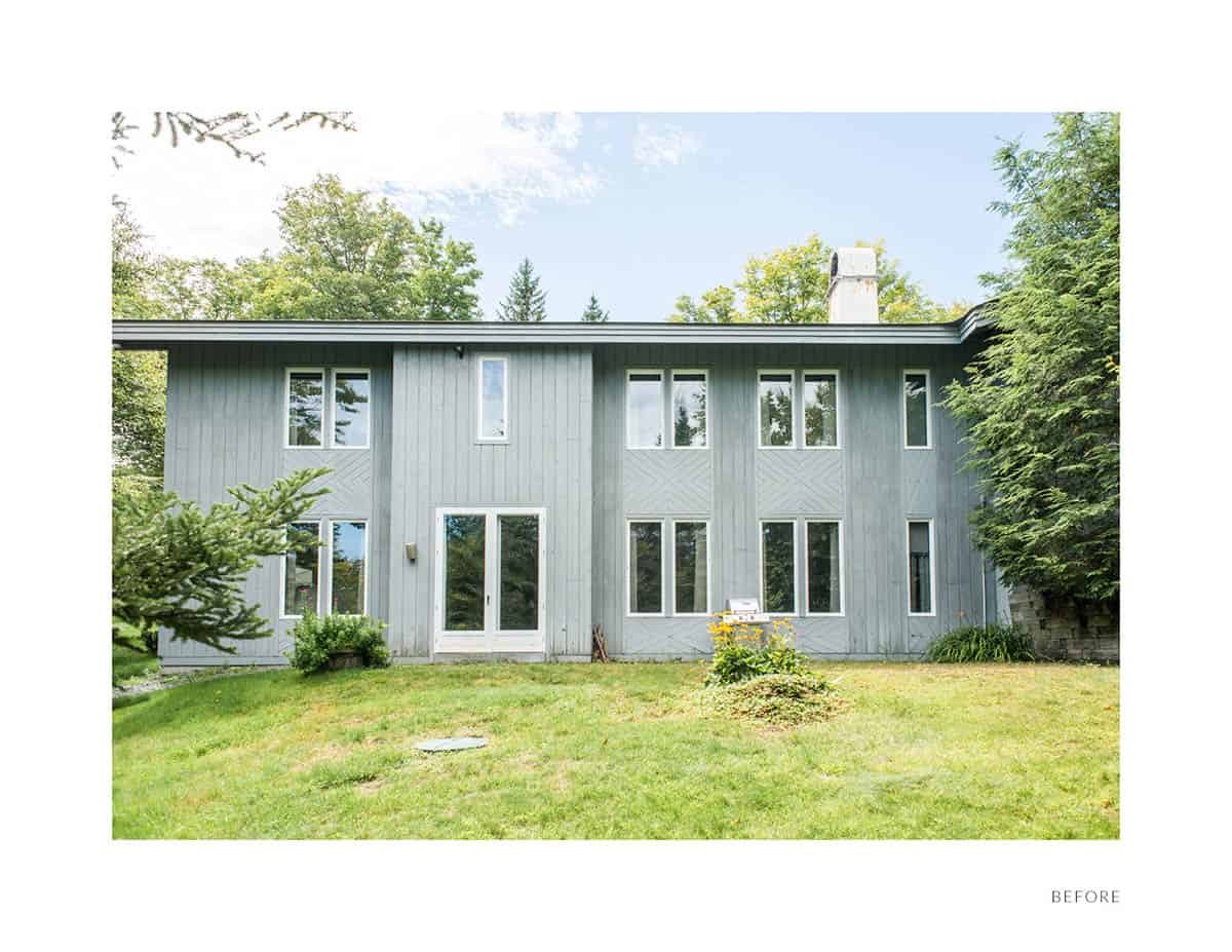 Before photo of original Vermont ski house with gray painted siding and white-trimmed windows prior to renovation