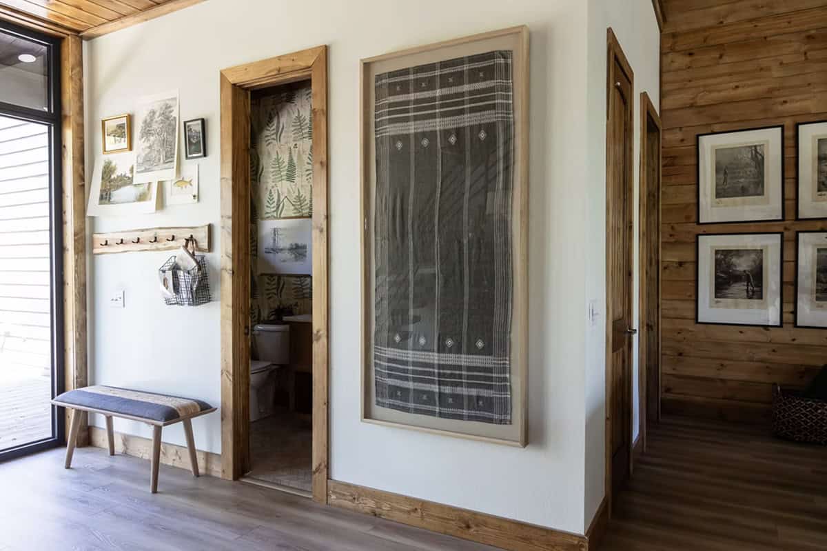 Entryway hallway with framed textile art, botanical wallpaper powder room, and wood-framed doors