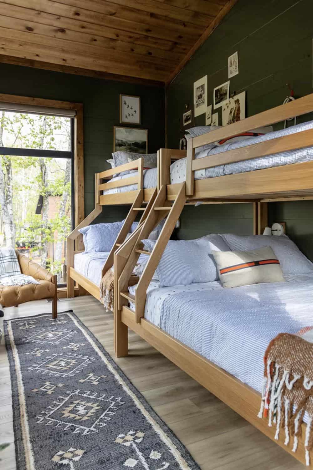 Bunk room with dark green shiplap walls, wood bunk beds, and tribal-pattern runner rug