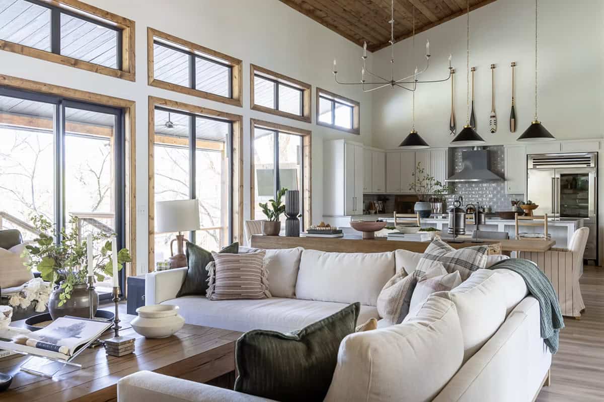Bright open living and kitchen area with large wood-framed windows and oar pendant lights