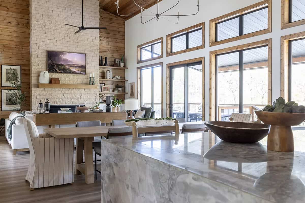 Kitchen island with marble countertop and dough bowl, overlooking dining area and stone fireplace wall