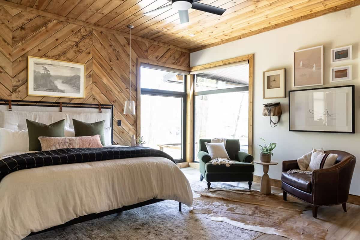 Main bedroom with chevron wood accent wall, iron bed frame, green and pink pillows, and sitting area