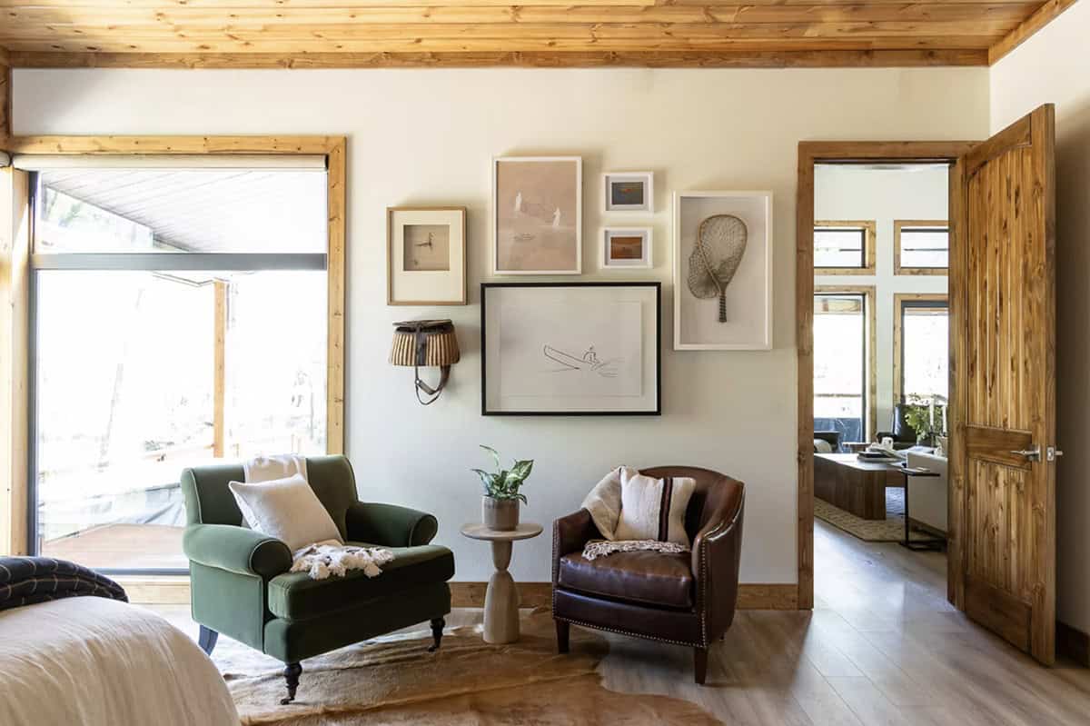 Bedroom sitting area with green velvet and leather chairs, fishing-themed gallery wall, and cowhide rug