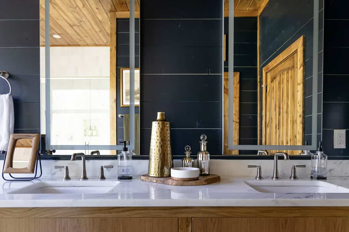 Double sink marble vanity close-up with brass vase, glass bottles, and dual rectangular mirrors
