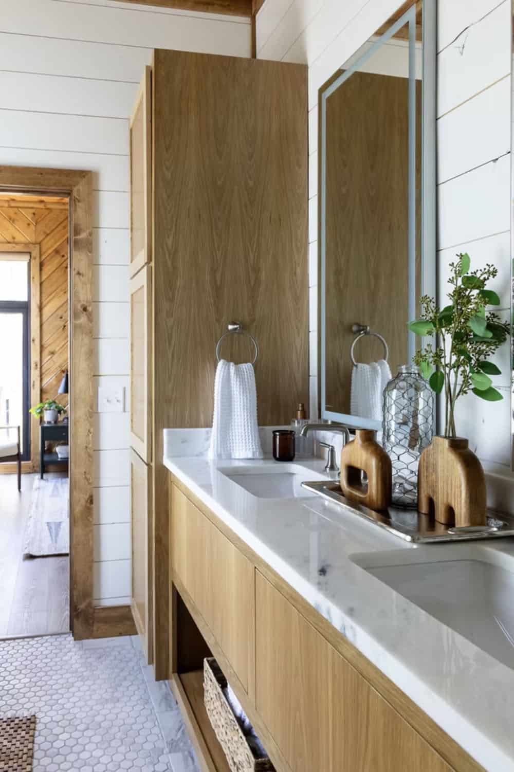 Ensuite bathroom with wood floating vanity, marble countertop, rectangular mirror, and woven baskets below